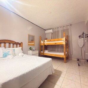 A bedroom with a bunk bed, a bedside table with a mirror, a hanging laundry rack, and a tiled floor.