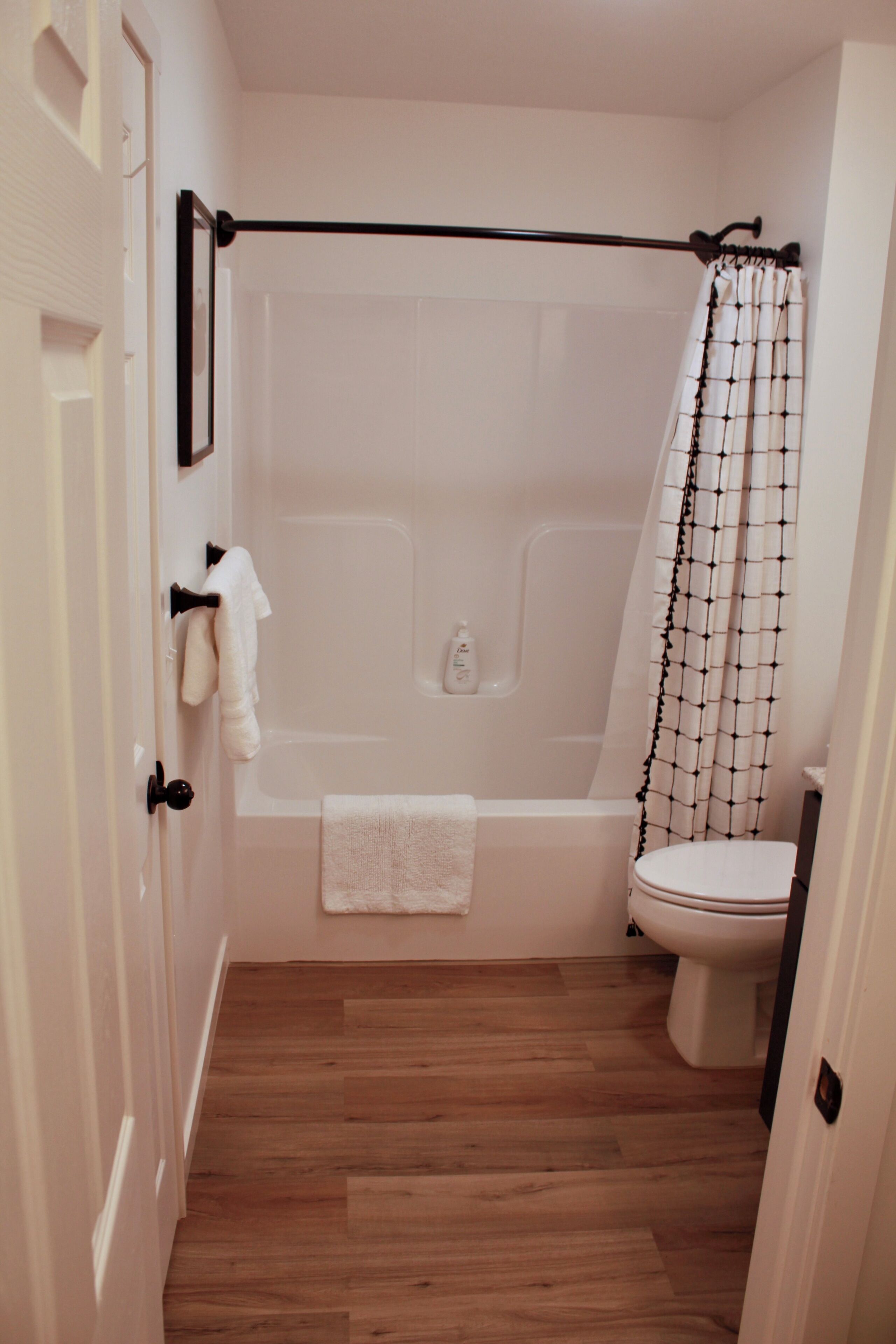 A bathroom with a bathtub, toilet, and a shower curtain.