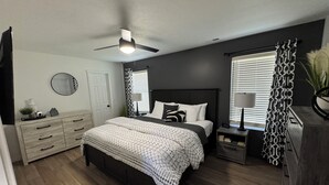 A bedroom with a bed, dresser, nightstands, and a ceiling fan. - Husker Getaway
 (Lincoln)