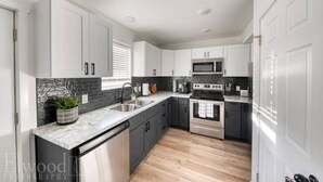 A modern kitchen with white cabinets, a black backsplash, and a stainless steel oven. - Husker Getaway
 (Lincoln)