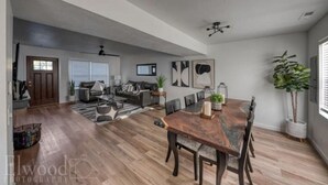 A spacious living room with a large wooden dining table, a fireplace, and a view of the adjacent kitchen. - Husker Getaway
 (Lincoln)