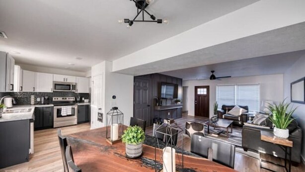 A modern kitchen with white cabinets, a central island, and a dining area with a wooden table and chairs. - Husker Getaway
 (Lincoln)