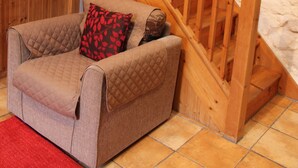 Una escalera de madera con una silla acolchada y un tapete rojo en una habitación con pared texturizada.