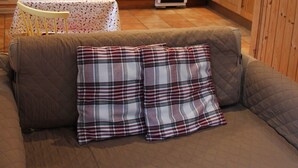 Una cocina acogedora con armarios de madera, una mesa de comedor y un sofá con cojines escoceses.