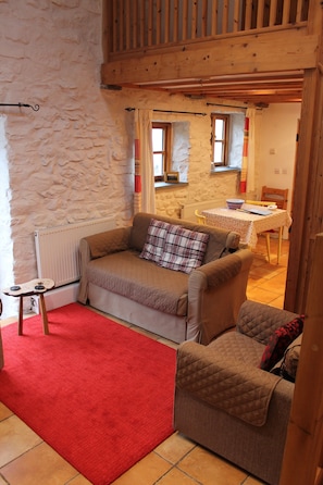 Une pièce chaleureuse avec une moquette rouge, un canapé marron et un plafond en bois.