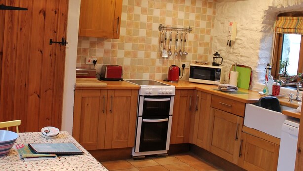 Una cocina con armarios de madera, salpicadero de azulejos y una zona de comedor con mesa y sillas.