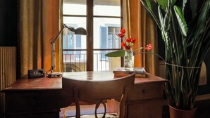 Uma mesa com uma luminária, um vaso com flores e uma planta em vaso.