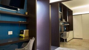 A modern room with a flat-screen TV, bookshelves, a chair, and a desk area. - Luxury Suite Fori Imperiali (Roma)