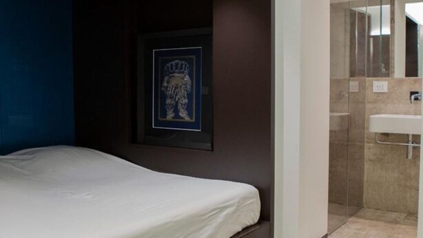 A hotel room with a bed, a framed picture on the wall, and a glass shower enclosure. - Luxury Suite Fori Imperiali (Roma)