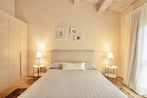 A bedroom with a bed, two bedside lamps, a headboard, and three framed pictures on the wall.
