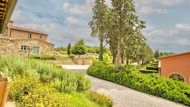 A stone building with a gravel path, surrounded by lush greenery and trees.