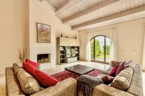 Ein geräumiges Wohnzimmer mit Kamin, einer großen Sofagarnitur und einem Bücherregal.