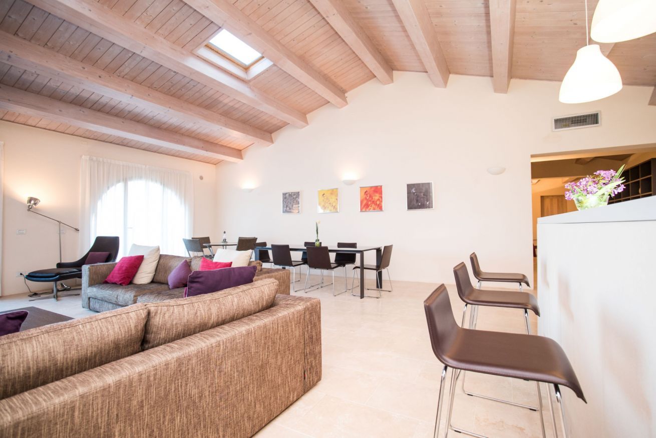 Uma sala de estar ampla com teto alto, uma mesa de jantar e mobiliário moderno.