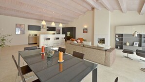 A modern living space with a dining area, kitchen, and seating area.