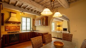 Una cocina con armarios de madera, horno empotrado y comedor con sillas de mimbre y una mesa.