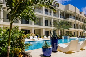 Un hotel con piscina, sillas de descanso y plantas en macetas.
