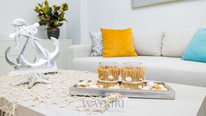 A neatly arranged table with a starfish, seashells, and straw cups, set against a white sofa with a yellow pillow. - Wariruri 2-07 Luxurious Apartment, private balcony! (Noord)