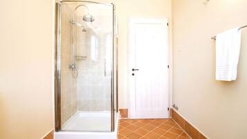 A bathroom with a glass-enclosed shower, a white door, and a towel rack.