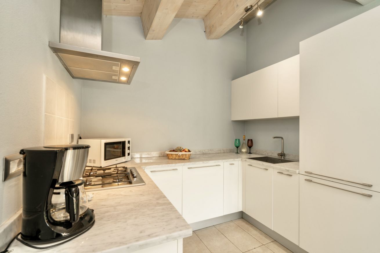 A modern kitchen with white cabinets, a built-in microwave, a coffee maker, and a gas stove.