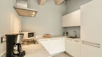 A modern kitchen with white cabinets, a built-in microwave, a coffee maker, and a gas stove.
