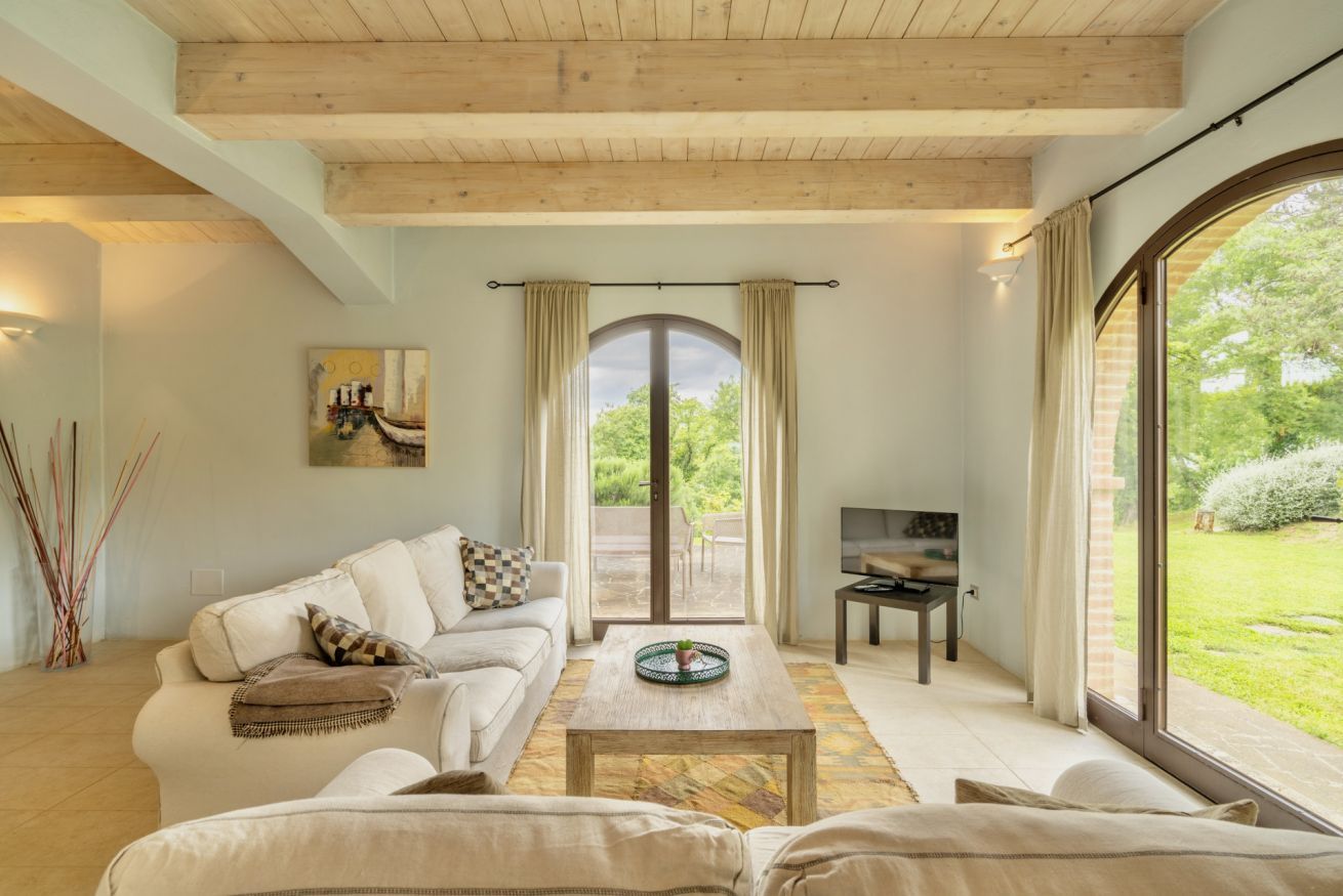 A spacious living room with a large window, a sofa, a coffee table, and a TV.