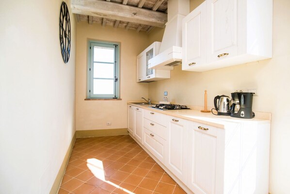 A compact kitchen with white cabinets, a window, and basic appliances.