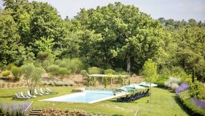 A pool area with lounge chairs and a pergola.