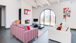 A modern living room with a fireplace, a large window, and a television.
