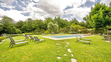 Un jardin avec une piscine, des chaises longues et une pelouse bien entretenue.