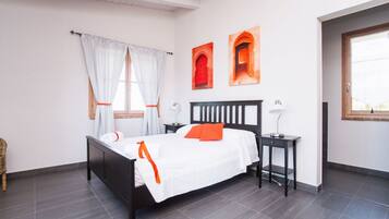 Une chambre à coucher bien rangée, avec un lit, des tables de chevet et une fenêtre avec des rideaux.