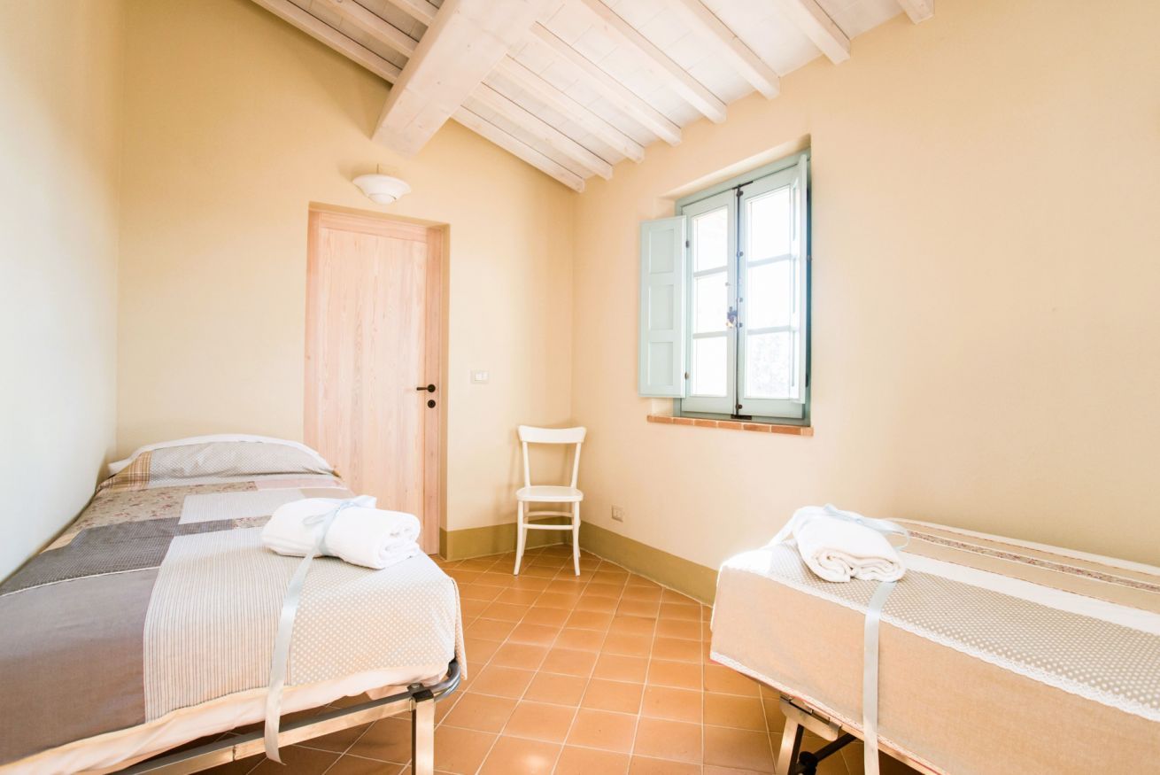 Een slaapkamer met een bed, een stoel, een klein tafeltje en een raam.