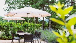 Une terrasse extérieure avec une table et des chaises, entourée d’une vég étation luxuriante et d’arbres.