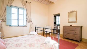 A bedroom with a bed, a chair, a dresser, and a mirror.