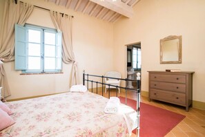 Un dormitorio con cama, una silla, cómoda y espejo.