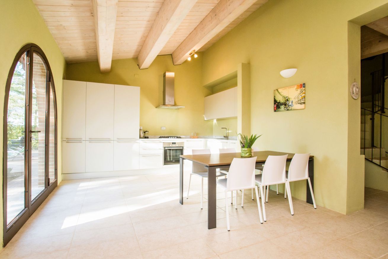 Une cuisine moderne avec des meubles blancs, une table à manger avec des chaises et une grande fenêtre.