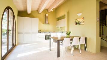 Une cuisine moderne avec des meubles blancs, une table à manger avec des chaises et une grande fenêtre.