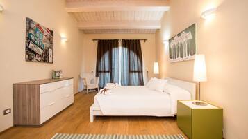 A bedroom with a bed, bedside table, dresser, and artwork on the walls.