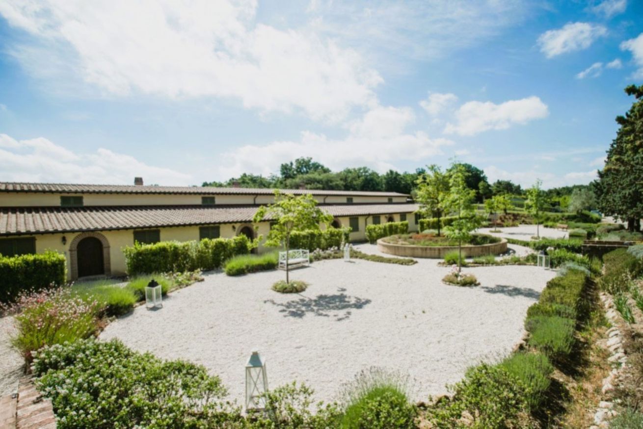 A courtyard with a building, gravel paths, and greenery.