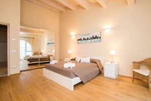 Ein modernes Schlafzimmer mit einem großen Bett, Nachttischen, einem Spiegel und einem Stadtbild.
