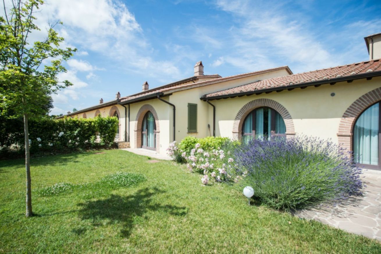 A house with a well-maintained lawn, a garden with lavender, and a clear blue sky.