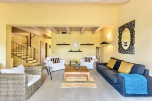 A living room with a staircase, two sofas, a coffee table, and a mirror.