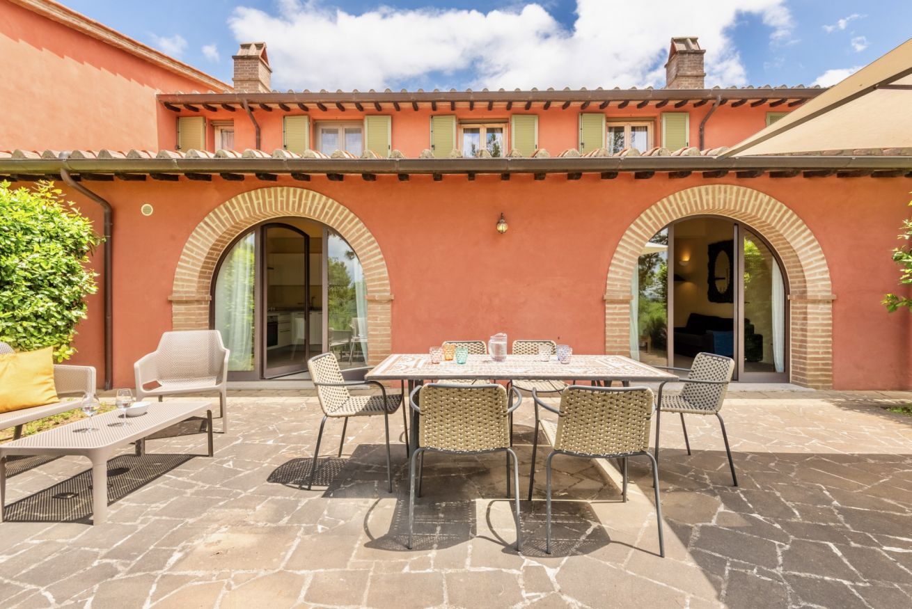 Eine Terrasse im Freien mit Tisch und Stühlen, einer Couch und einem Steinboden.