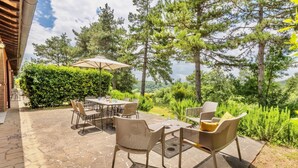 An outdoor patio with stone flooring, wicker furniture, and a view of a forested area.