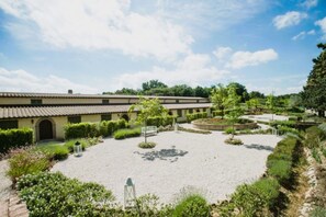 A courtyard with a building, gravel paths, and greenery.