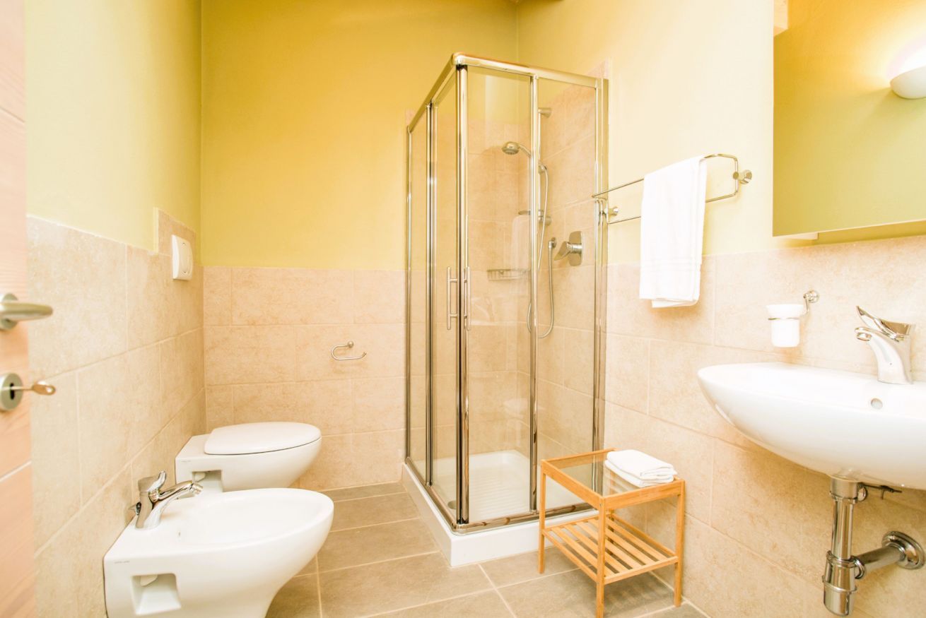 Un bagno con doccia vetro-muraria, un water, un bidet e un lavandino.