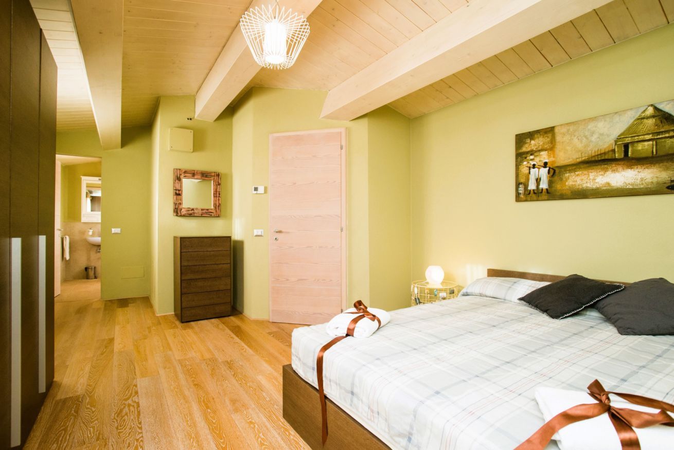 Ein Schlafzimmer mit einem Bett, einer Kommode, einem Spiegel, einer Tür und einem Bild an der Wand.