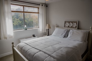 Relax in this serene bedroom with a large bed and a cozy reading nook.