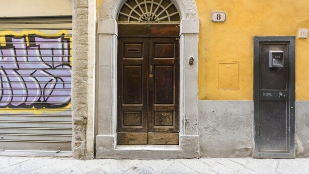 A building entrance with a brown door, a number 8 sign, and a utility box. - Madame Betta apartment in Florence by Mmega (Firenze)