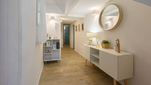 A hallway with a white console table, a round mirror, and a shelf with decorative items. - Madame Betta apartment in Florence by Mmega (Firenze)