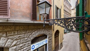 A narrow street with a stone archway, a storefront with a luggage storage sign, and a street lamp. - Madame Betta apartment in Florence by Mmega (Firenze)